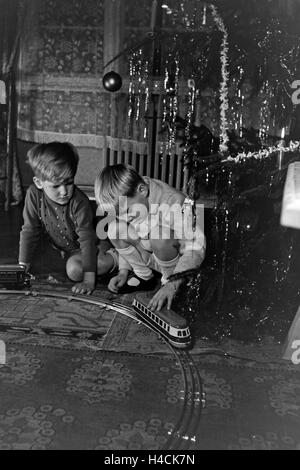 Zwei Jungen Spielen bin Weihnachtsabend Unter Dem Tannenbaum Mit der Neuen Modelleisenbahn, Deutschland 1938. Zwei Jungs spielen mit dem neuen Modell trainieren unter dem Weihnachtsbaum, Deutschland der 1930er Jahre Stockfoto