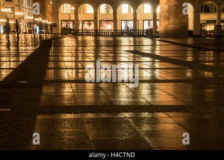 Blick auf großen nassen Platz in der Stadt reflektiert beleuchtete Gebäuden an einem regnerischen Abend Stockfoto