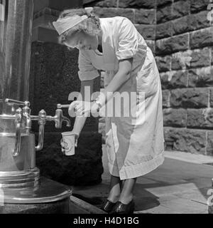 Eine Krankenschwester Im Kurbad Bad Homburg eine Einer Heilwasserquelle, 1930er Jahre Deutschland. Eine Krankenschwester auf einen Brunnen Heilwasser bei Kurort Bad Homburg, Deutschland der 1930er Jahre. Stockfoto