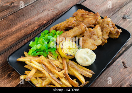 Fish And Chips mit hausgemachte Mayonnaise auf schwarzem Teller Stockfoto