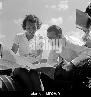 Ein Junger Mann Und Eine Junge Frau Ziehen Bei Einer Autofahrt sterben Hallwag Straßenkarte Zu Rate, 1930er Jahre Deutschland. Ein junges Paar mit Hallwag Straßenkarte, Deutschland der 1930er Jahre. Stockfoto