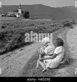 Zwei Junge Frauen einer Auf Einem Weg Zu Einem Kleinen Dorf Im Böhmerwald, Deutschland 1930er Jahre. Zwei junge Frauen sitzen auf dem Weg in ein kleines Dorf in der Böhmerwald-Region Deutschland der 1930er Jahre. Stockfoto