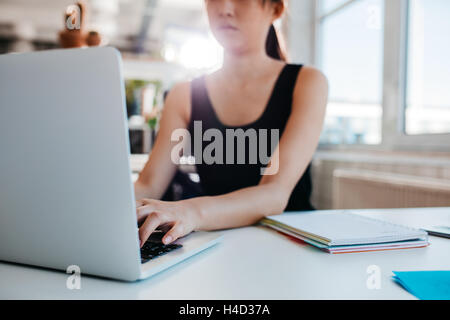 Aufnahme an Notebook im Büro arbeitet Frau zugeschnitten. Konzentrieren Sie sich auf Händen der weiblichen auf Laptoptastatur tippen. Stockfoto