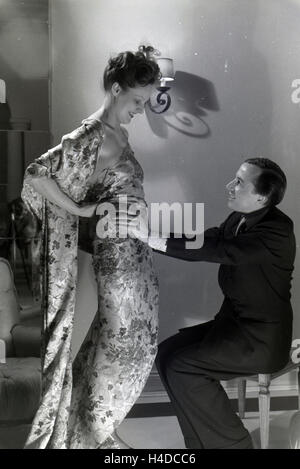 Der Modeschöpfer Heinz Schulze-Bibernell Und Ein Modell Bei der Anprobe Eines Kleides, Deutschland ca. 1939. Der Modeschöpfer Heinz Schulze-Bibernell und ein Modell, das versucht, ein Kleid, Deutschland ca. 1939. Stockfoto