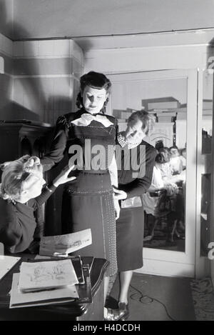Ein Modell Bei der Anprobe Eines Kleides Mit Modeschpferin Annemaria Geise Und Einer Assistentin Im Studio; Deutschland ca. 1939. Ein Modell, das versucht einer Kleids mit Modedesignerin Annemaria Geise und Assistentin im Studio, Deutschland ca. 1939. Stockfoto