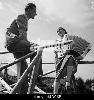 Ein Junger Mann Und Eine Frau Mit Einem Akkordeon, 1930er Jahre Deutschland. Ein junger Mann und eine Frau mit einem Akkordeon, Deutschland der 1930er Jahre. Stockfoto