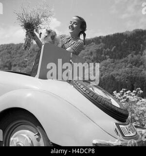 Eine Frau Mit Einem Blumenstrauß bin Kofferraum Einems Mercedes Benz Cabrio, Deutschland 1930er Jahre. Eine Frau mit einem Blumenstrauß an der Rückseite des Mercedes Benz Cabrio, Deutschland der 1930er Jahre. Stockfoto
