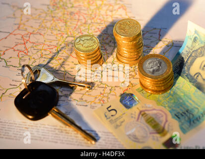 Fahrzeugschlüssel und Haufen von einem Pfund-Münzen um Fahrplan zeigt London Vereinigtes Königreich Stockfoto