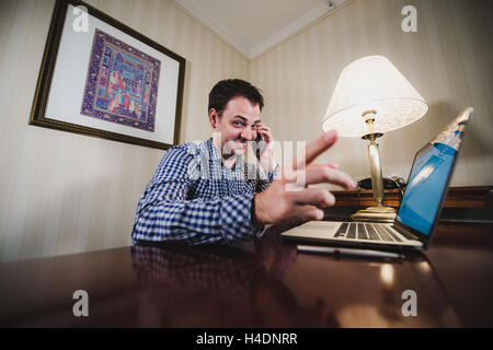 Geschäftsmann Punkt Finger auf Sie, glückliches Lächeln sitzt der Schreibtisch im Büro, Mobile Telefonieren mit Handy, hübscher Junge Mann machen Anruf, auf Kamera Stockfoto