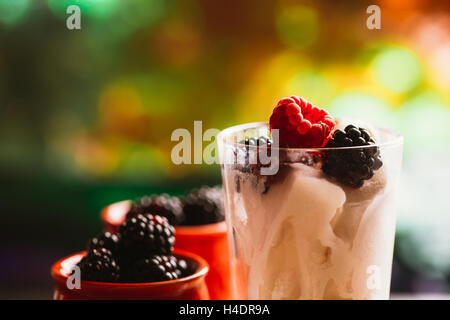 BlackBerry-Eis in eine Tasse und ein Glas auf einem Hintergrund von Holzbrettern und ein unscharfes grün. Stockfoto