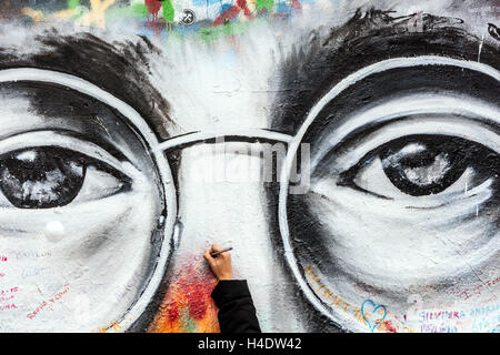 John Lennon Wall Prag Eine Hand schreibt eine Botschaft zwischen Johnnys Augen mit Brille, Straßengraffiti Stockfoto