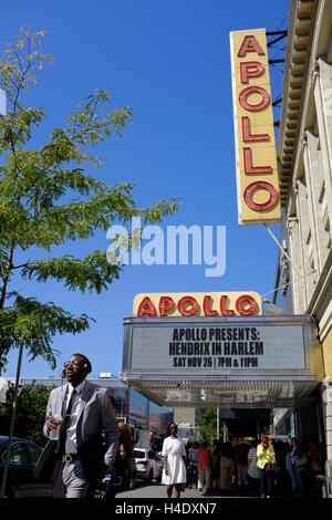 Fußgänger an der 125th Street mit Zeichen des Apollo Theater am Eingang des Theaterin Hintergrund. Harlem, New York City, USA Stockfoto