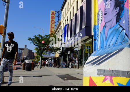 Fußgänger an der 125th Street mit dem Zeichen des Apollo Theater im Hintergrund. Harlem, New York City, USA Stockfoto