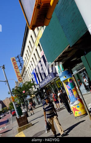 Fußgänger an der 125th Street mit dem Zeichen des Apollo Theater im Hintergrund. Harlem, New York City, USA Stockfoto