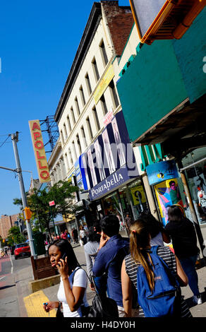 Fußgänger an der 125th Street mit dem Zeichen des Apollo Theater im Hintergrund. Harlem, New York City, USA Stockfoto