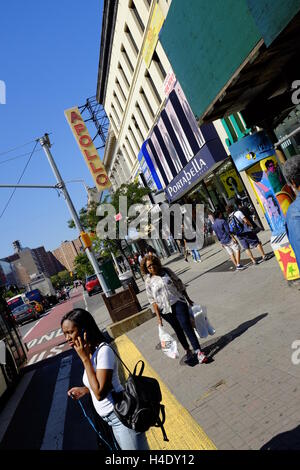 Fußgänger an der 125th Street mit dem Zeichen des Apollo Theater im Hintergrund. Harlem, New York City, USA Stockfoto