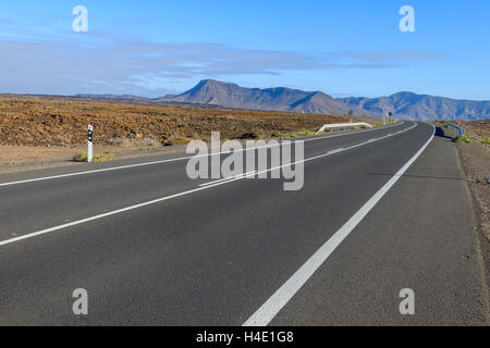 Straße in der Wüstenlandschaft und vulkanischen Bergen im Hintergrund, Fuerteventura, Kanarische Inseln, Spanien Stockfoto