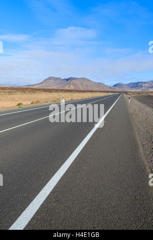 Straße in der Wüstenlandschaft und vulkanischen Bergen im Hintergrund, Fuerteventura, Kanarische Inseln, Spanien Stockfoto