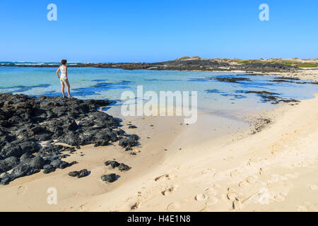 Junge Womand stehen auf Felsen im Strand Lagune in El Cotillo Stadt, Fuerteventura, Kanarische Inseln, Spanien Stockfoto