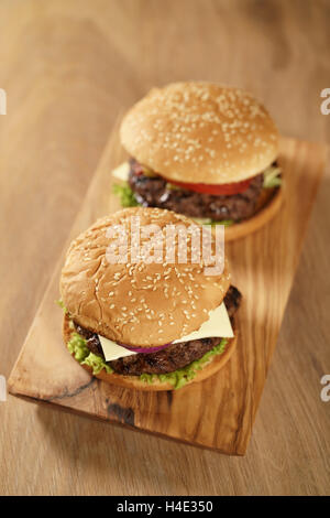 zwei hausgemachte Burger auf Oliven Brett auf Eichentisch Stockfoto