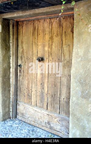 Eine dunkle Holztür auf einer steinernen Mauer mit einer Skulptur. Stockfoto