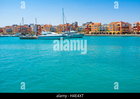 Der malerische Blick auf die bunten Gebäude in Hurghada Marina mit den weißen Yachten im Hafen, Ägypten. Stockfoto