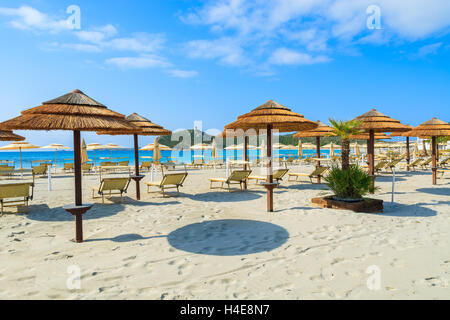 Liegestühle mit Sonnenschirmen am weißen Sandstrand in Porto Giunco Bucht, Insel Sardinien, Italien Stockfoto