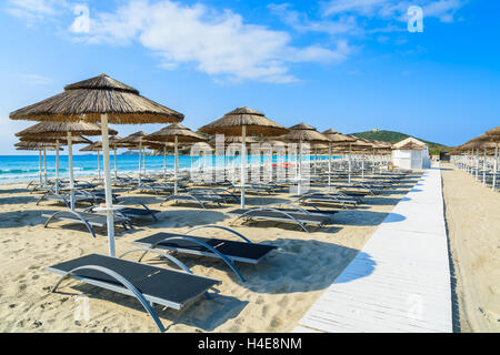 Weg entlang Liegestühle mit Sonnenschirmen am weißen Sandstrand in Porto Giunco Bucht, Insel Sardinien, Italien Stockfoto