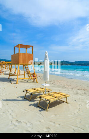 Liegestühle und Rettungsschwimmer Turm am weißen Sandstrand in Porto Giunco Bucht, Insel Sardinien, Italien Stockfoto