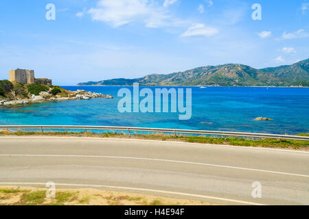 Küstenstraße entlang der azurblauen Meer mit Schloss im Hintergrund in der Nähe von Porto Giunco Hafen, Insel Sardinien, Italien Stockfoto