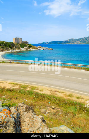 Küstenstraße entlang der azurblauen Meer mit Schloss im Hintergrund in der Nähe von Porto Giunco Hafen, Insel Sardinien, Italien Stockfoto