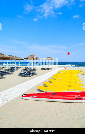 PORTO GIUNCO Strand, Sardinien - 25. Mai 2014: gelbe Kajaks und Sonnenschirme mit Sonnenliegen am Strand von Porto Giunco, Insel Sardinien, Italien. Süden der Insel hat die schönsten Strände in Europa. Stockfoto