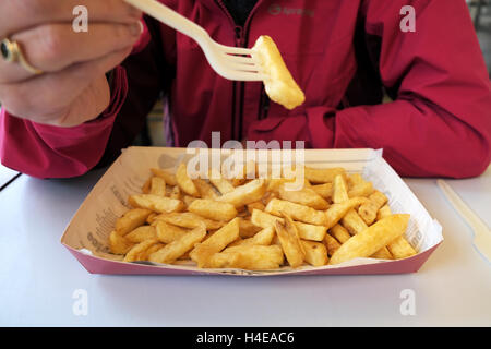 Eine Dame, die einen Teil der frisch zubereiteten Fisch und Chips aus einem Harry Ramsden Fish &amp; Chips-Shop Essen Stockfoto