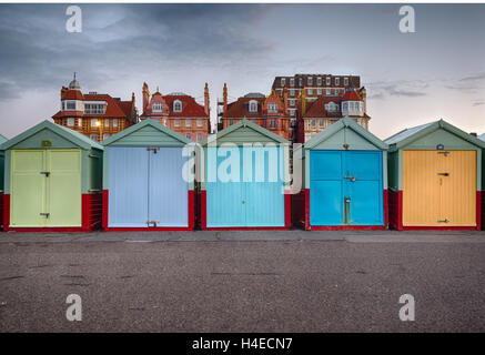 Reihe von bunten Strandhäuschen auf der Promenade in Hove, Sussex, stürmische grauen Himmel hinter Stockfoto