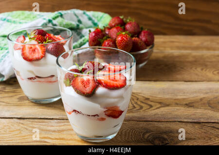 Sommer-Dessert mit Schlagsahne und Erdbeeren auf hölzernen Hintergrund. Geschichtete Dessert mit frischen Reifen Erdbeeren. Stockfoto