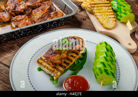 Klebrige Huhn mit pikanter Sauce, geröstete Panini mit grobkörnigem Salz und Olivenöl sowie Gurke kebab Stockfoto