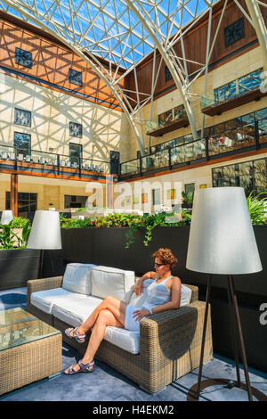 ARLAMOW HOTEL, Polen - 3. August 2014: junge Frau sitzt auf einem Sofa im schönen offenen Lobby Restaurant in Arlamow Hotel. Dieses luxuriöse Resort befindet sich im Bieszczady-Gebirge. Stockfoto