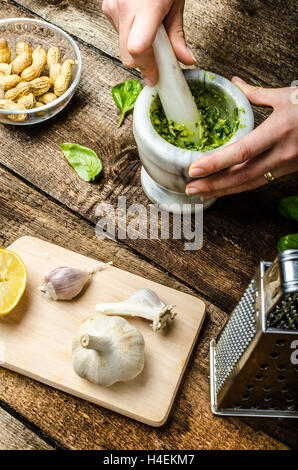 Pesto - Basilikum-Käse, Nüssen und Olivenöl im Mörser zu machen Stockfoto