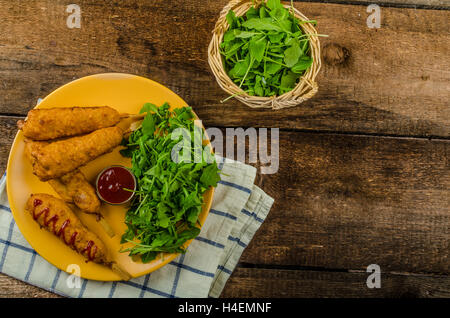 Corndog mit frischem Rucola-Salat und feuerverzinkten, Holztisch Stockfoto