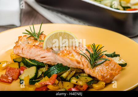 Lachs gebacken mit Thymian und mediterranem Gemüse auf Holz Tisch mit Platte Stockfoto