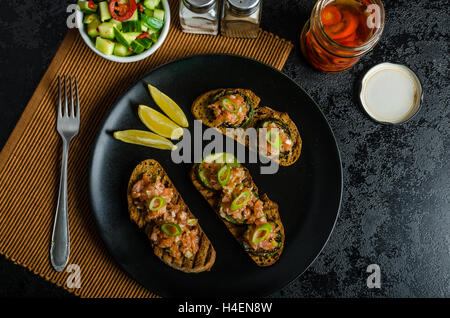 Lachstartar auf knusprigen Toast mit knackigen Gurkensalat und Chili Pfeffer Stockfoto