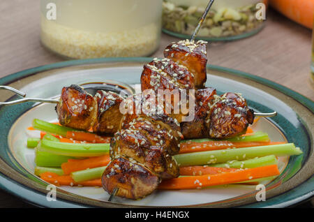 Klebrige Teriyaki-Hähnchen-Spieße mit knackigen Krautsalat - bestreut mit knackigen Sesam, tschechisches Bier Stockfoto