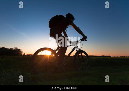 Junge Erwachsene reiten Skilanglauf Fahrrad bei Sonnenuntergang Stockfoto