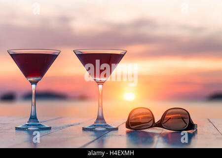 Zwei Cocktails und Sonnenbrillen in einem Strandrestaurant, Flitterwochen, Sonnenuntergang Stockfoto