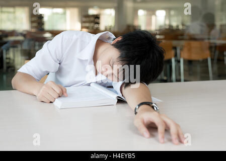 Müde asiatische Studentin oder asiatischen jungen Mann mit Büchern in Bibliothek an der Universität zu schlafen. Student, Ausbildung, Sitzung, Prüfungen Stockfoto
