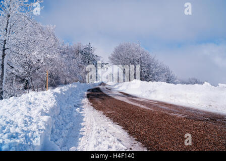 Straße im Schnee mit bewölktem Himmel Stockfoto