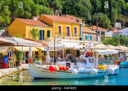 KIONI Hafen, Insel ITHAKA - SEP 19, 2014: Angelboot/Fischerboot auf türkisfarbenes Meerwasser in Kioni Hafen mit bunten Häusern. Griechenland ist ein sehr beliebtes Urlaubsziel in Europa. Stockfoto