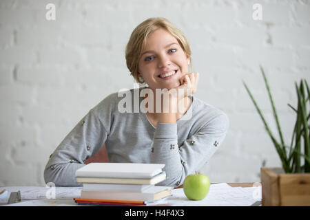 Porträt von lächelndes Mädchen am Schalter mit Büchern und Apfel Stockfoto