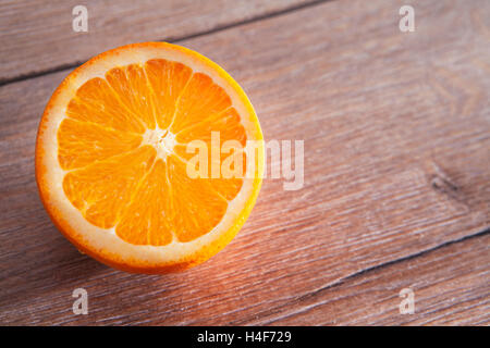 die Hälfte der Orange auf auf einem Holztisch. Eine Menge an freiem Speicherplatz Stockfoto