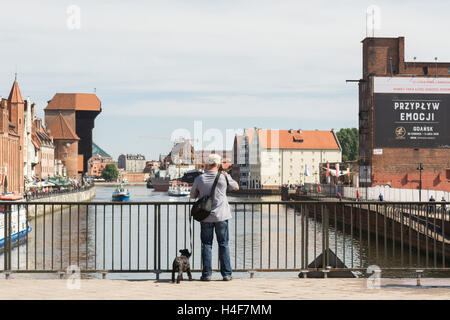 Danzig - Mann mit dem Fotografieren der klassischen Ansicht von Gdansk Waterfront und Kran von der grünen Brücke über den Fluss Mottlau Stockfoto